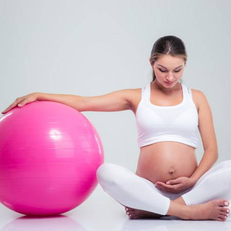 Pregnant woman sitting on the floor with fitness ball